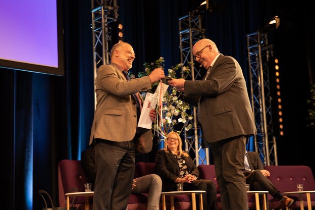 Prof. Dr. Ralph Stengler und Prof. Dr. Arnd Steinmetz grüßen sich auf der Bühne