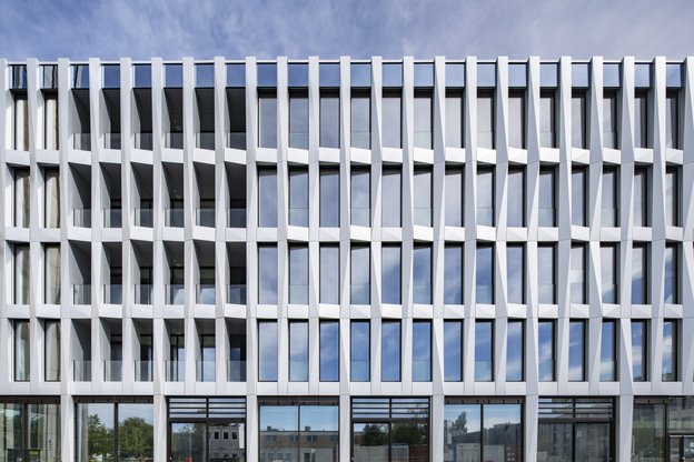 Nahaufnahme Fassade Studierendenhaus vor blauem Himmel, der sich in den Fenstern spiegelt