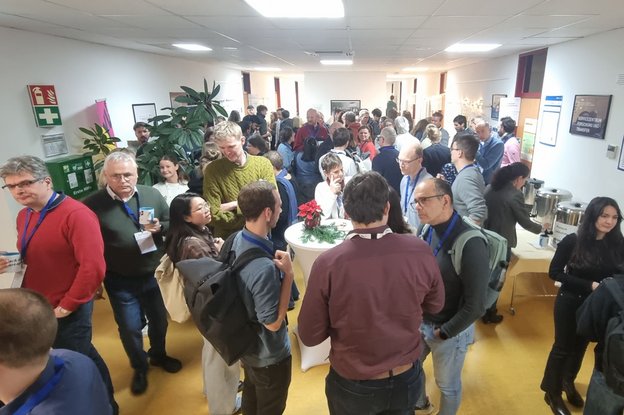 Many people conversing in a room with standing tables