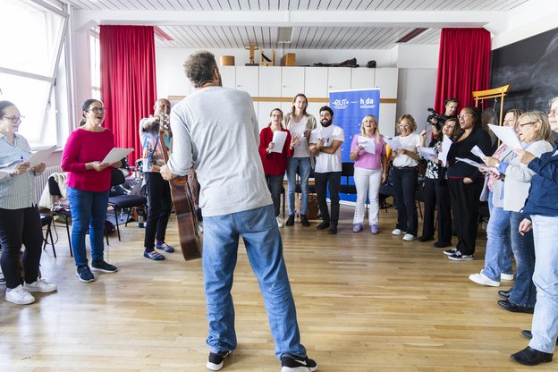 Chor steht im Halbkreis, vor ihnen ein Dirigent
