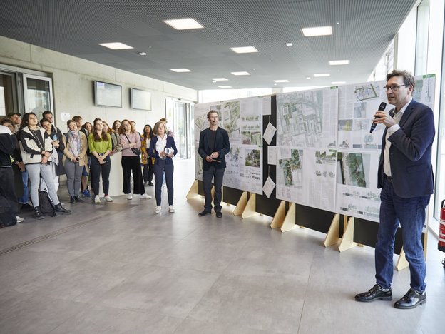h_da-Kanzler Thomas Bartnitzki präsentiert die Ausstellung vor Publikum im Foyer des Studierendenhauses